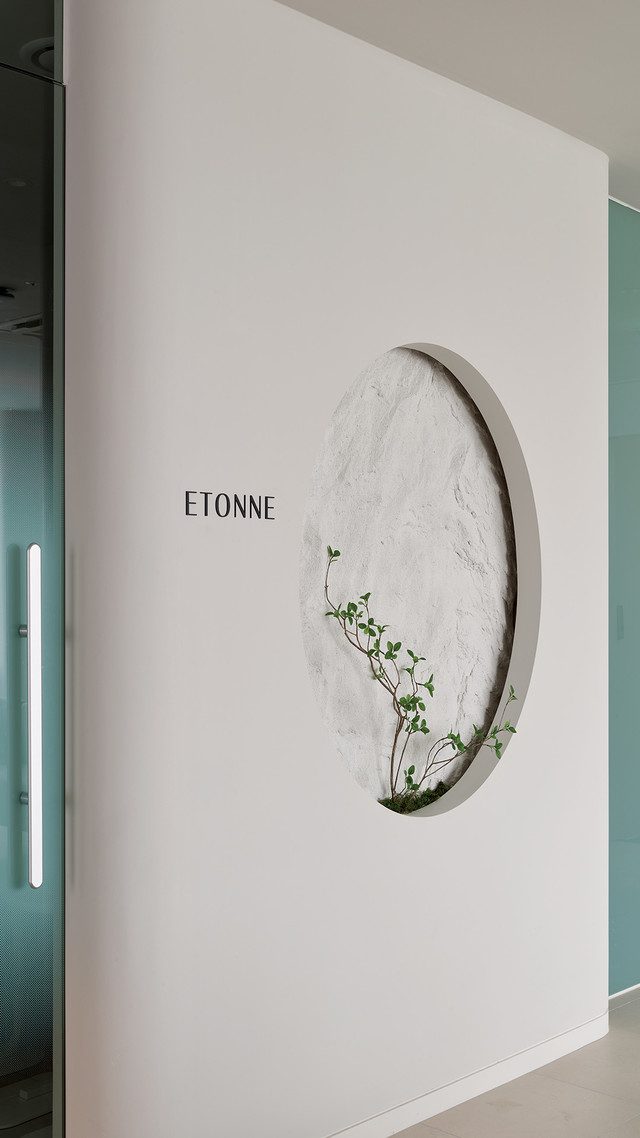 'ETONNE' 글자와 초록 식물이 있는 원형 조형물 인테리어 벽면