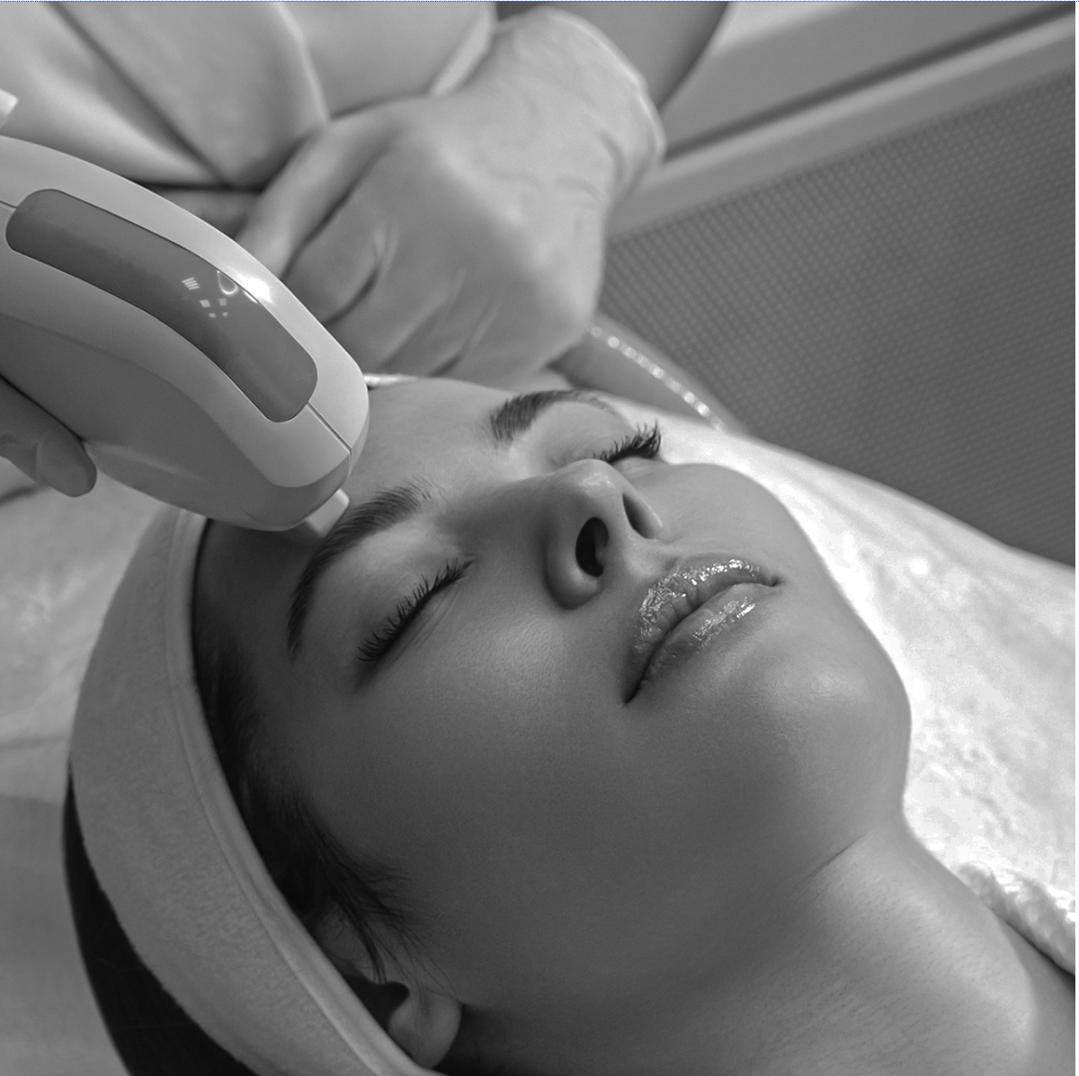 Black-and-white photo of a provider holding a laser device to a patient's face