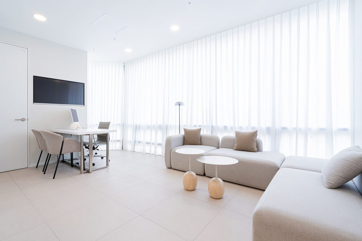 Consultation room with sheer curtains, a desk with a skull model, and a lounge sofa