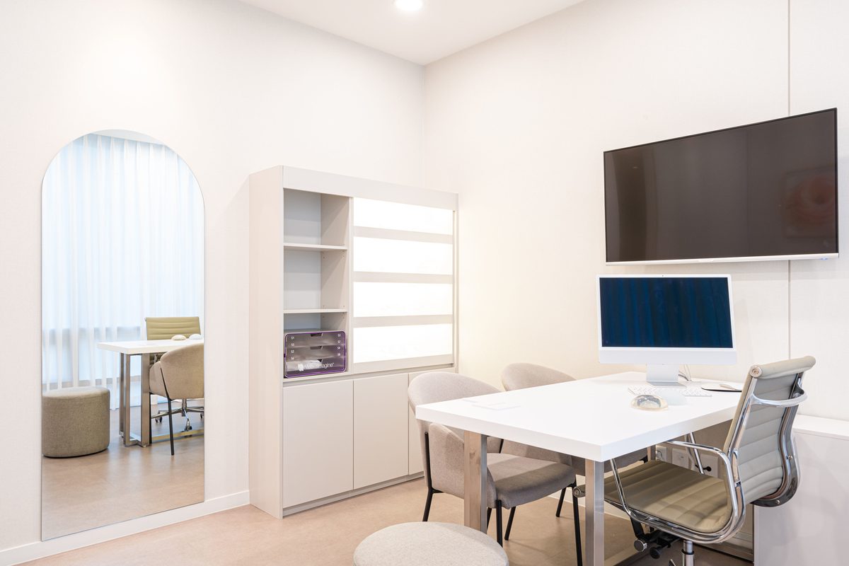 Consultation room with an arched mirror, open shelving, and a glass desk
