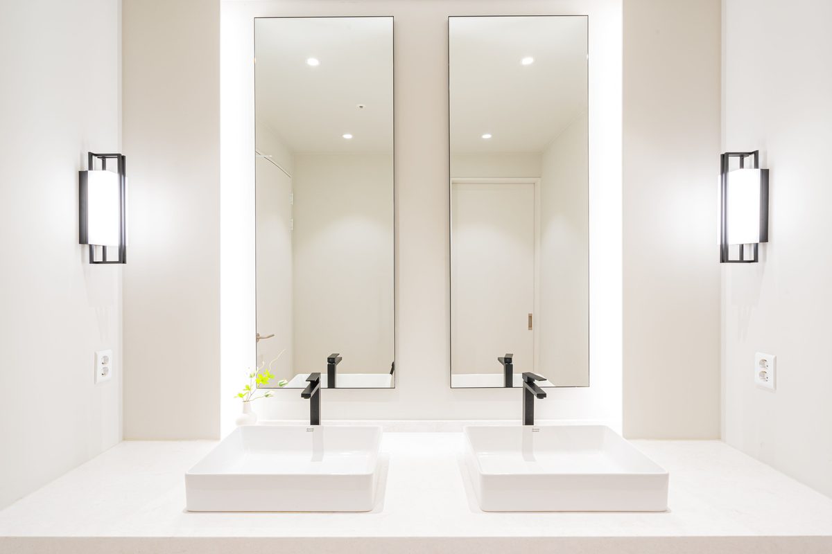 Two vessel sinks with tall mirrors and black faucets