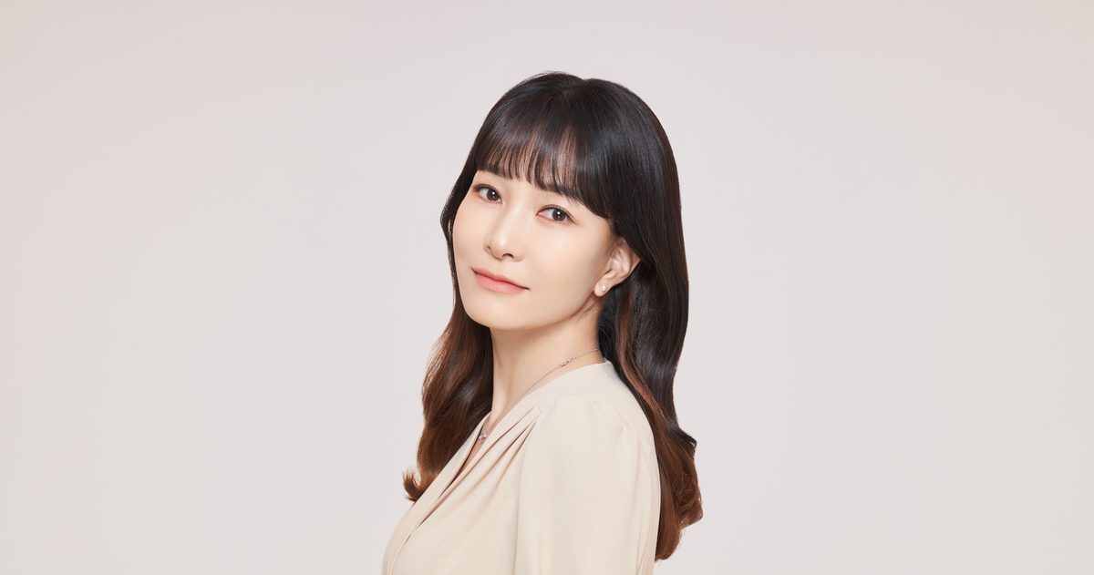 베이지색 상의를 입고 옆으로 고개를 돌려 정면을 응시하는 여성의 인물 사진