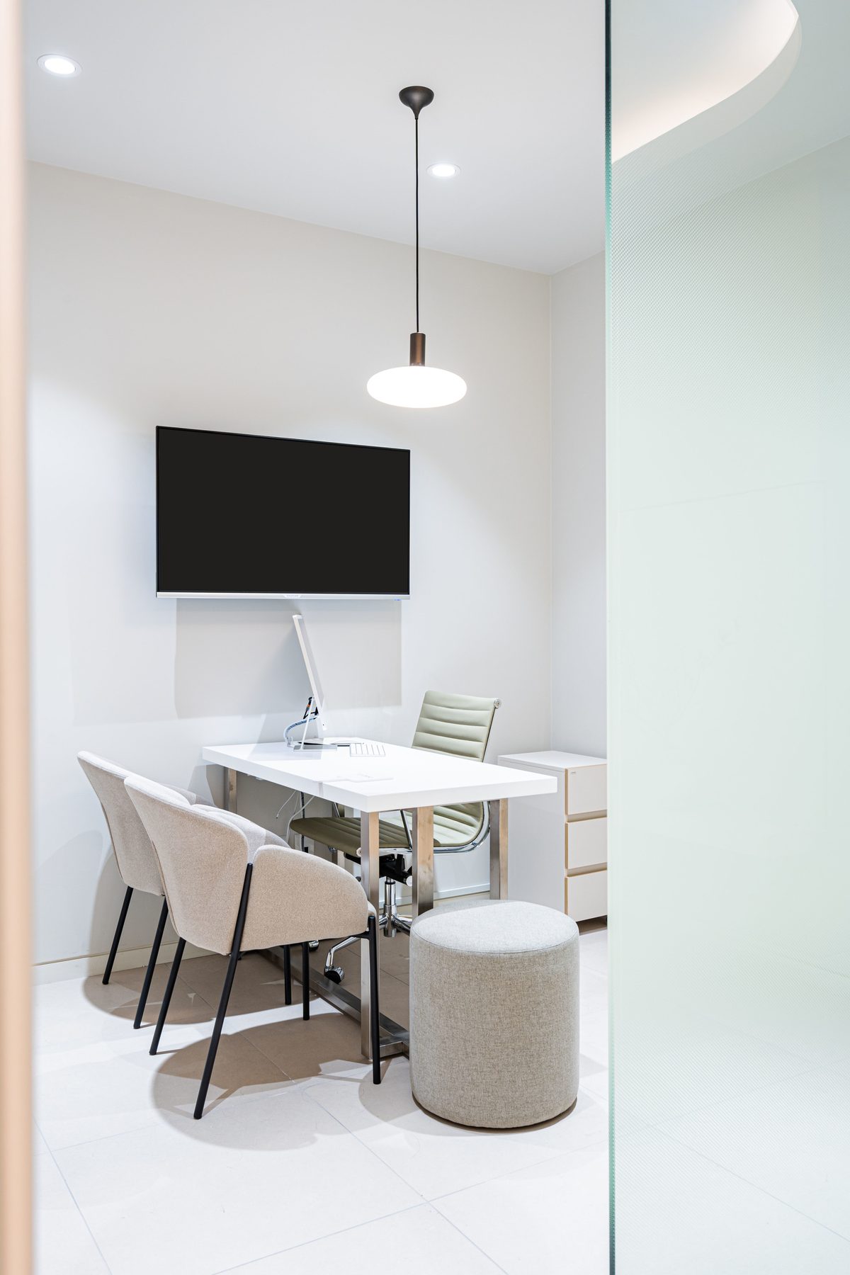 Consultation room with a round pendant light, wall-mounted screen, and desk